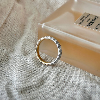 Two tone eternity ring in solid 14K yellow and white gold with lab-grown diamonds styled beside a perfume bottle.